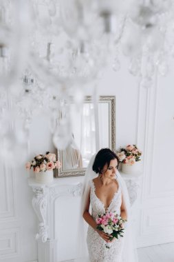 Beyaz gelinlik içinde güzel, genç bir gelin. Lüks içinde poz veriyor.        