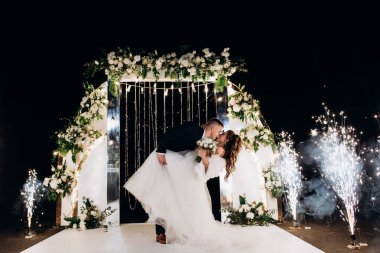 Genç bir düğün çifti, özel günlerinde güzel düğün süslemelerinin önünde romantik bir anın tadını çıkarır..