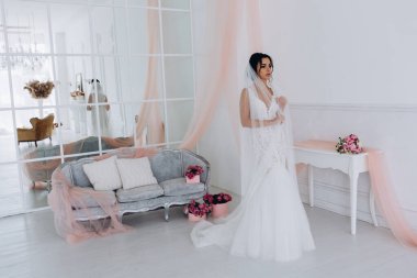 Beyaz gelinlik içinde güzel, genç bir gelin. Lüks içinde poz veriyor.        