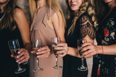 Stüdyoda şampanya kadehleriyle poz veren bir grup güzel genç kadın.