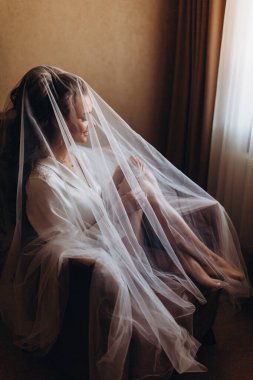 Beyaz peçeli mutlu genç gelinin portresi Sabahleyin sandalyede oturuyor    