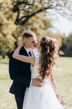 Genç bir çift düğün günlerinde güneşli bir yaz parkında romantik bir anın tadını çıkarır. Doğayla çevrili, birbirlerini sevgiyle öperler..