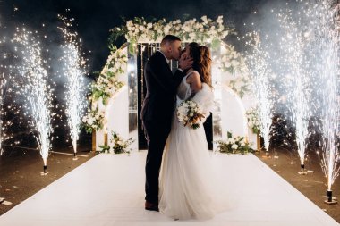 Genç bir düğün çifti, özel günlerinde güzel düğün süslemelerinin önünde romantik bir anın tadını çıkarır..