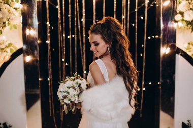 Genç ve güzel bir gelin, özel gününde göz kamaştırıcı düğün süslerinin önünde zarifçe poz verir..