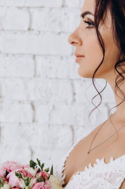 Beyaz tuğladan duvar arkasında güzel esmer gelinin yan görüntüsü 