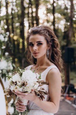 Genç ve güzel bir gelin, özel gününde göz kamaştırıcı düğün süslerinin önünde zarifçe poz verir..