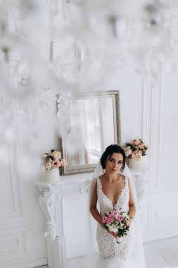 Beyaz gelinlik içinde güzel, genç bir gelin. Lüks içinde poz veriyor.        