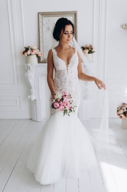 Beyaz gelinlik içinde güzel, genç bir gelin. Lüks içinde poz veriyor.        