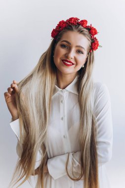 Uzun saçlı, çiçekli ve kameraya gülümseyen çekici bir genç kadın portresi.           