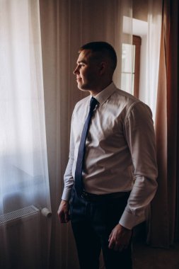 Takım elbiseli yakışıklı damat düğün törenine hazırlanıyor.       