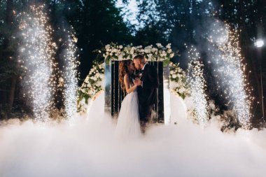 Genç bir düğün çifti, özel günlerinde güzel düğün süslemelerinin önünde romantik bir anın tadını çıkarır..