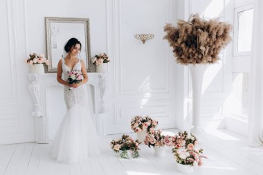 Beyaz gelinlik içinde güzel, genç bir gelin. Lüks içinde poz veriyor.        