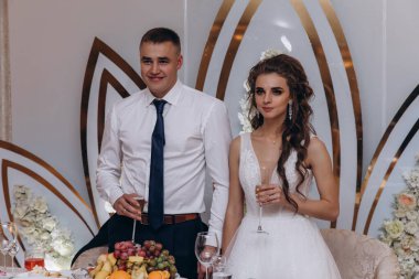 Gelin ve damat düğün resepsiyonunda şampanya kadehleri tutuyorlar.