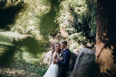 Güzel, mutlu gelin ve damat düğün günü parkta sarılıyorlar.      