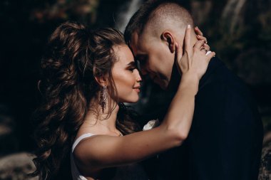 Güzel, mutlu gelin ve damat düğün günü parkta sarılıyorlar.      