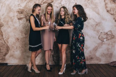 Stüdyoda şampanya kadehleriyle poz veren bir grup güzel genç kadın.