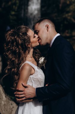 Güzel, mutlu gelin ve damat düğün günü parkta sarılıyorlar.      