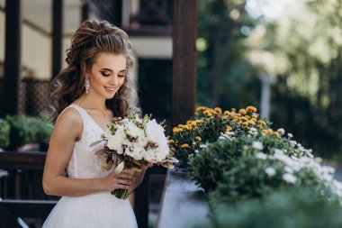 Mutlu genç gelin elinde bir buket çiçek tutuyor   