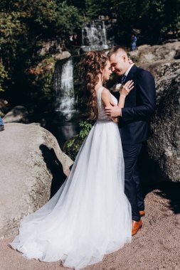 Güzel, mutlu gelin ve damat düğün günü parkta sarılıyorlar.      