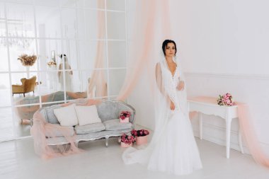 Beyaz gelinlik içinde güzel, genç bir gelin. Lüks içinde poz veriyor.        