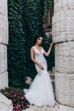 Gelin, antik taş duvarın önünde zarifçe poz verir. 