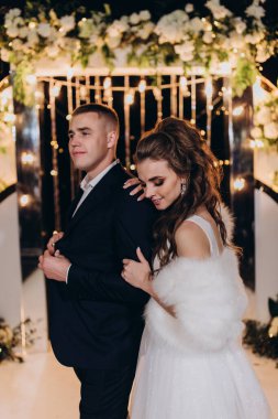 Genç bir düğün çifti, özel günlerinde güzel düğün süslemelerinin önünde romantik bir anın tadını çıkarır..