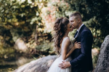 Güzel, mutlu gelin ve damat düğün günü parkta sarılıyorlar.      