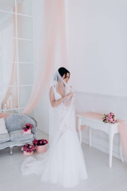 Beyaz gelinlik içinde güzel, genç bir gelin. Lüks içinde poz veriyor.        