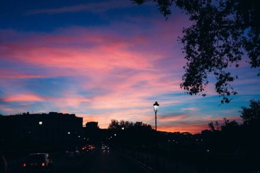 Karanlık şehir manzarasının üzerinde güzel bir günbatımı gökyüzü