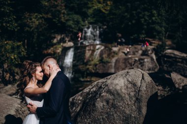 Güzel, mutlu gelin ve damat düğün günü parkta sarılıyorlar.      