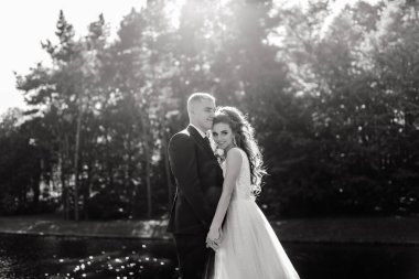 Güzel, mutlu gelin ve damat düğün günü parkta sarılıyorlar.      