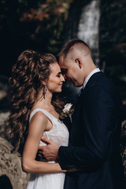 Güzel, mutlu gelin ve damat düğün günü parkta sarılıyorlar.      