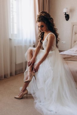 Güzel gelin, uzun kıvırcık saçlı, beyaz gelinlikli, sabahları ayakkabı giyen.