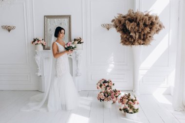 Beyaz gelinlik içinde güzel, genç bir gelin. Lüks içinde poz veriyor.        