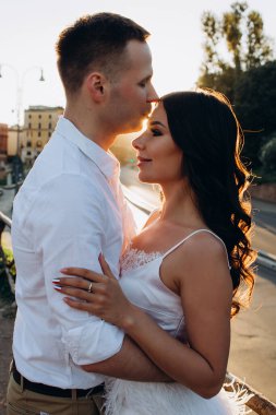 Mutlu genç çift gün batımında şehir caddesinde birbirlerine sarılıyorlar.