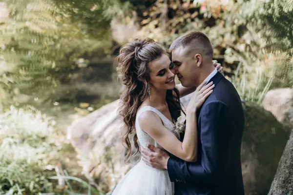 Genç bir çift düğün günlerinde güneşli bir yaz parkında romantik bir anın tadını çıkarır. Doğayla çevrili, gülümsüyor ve birbirlerine sevgiyle sarılıyorlar..