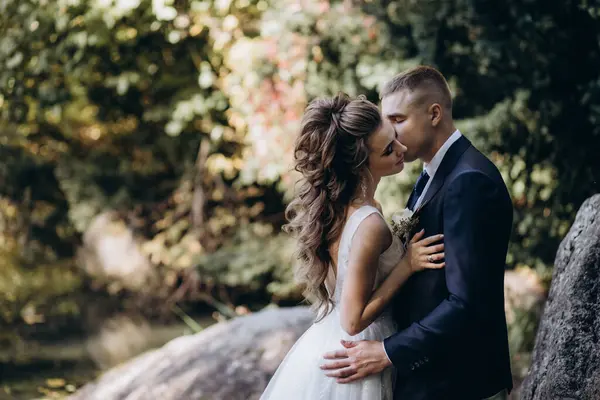 Güzel, mutlu gelin ve damat düğün günü parkta sarılıyorlar.      