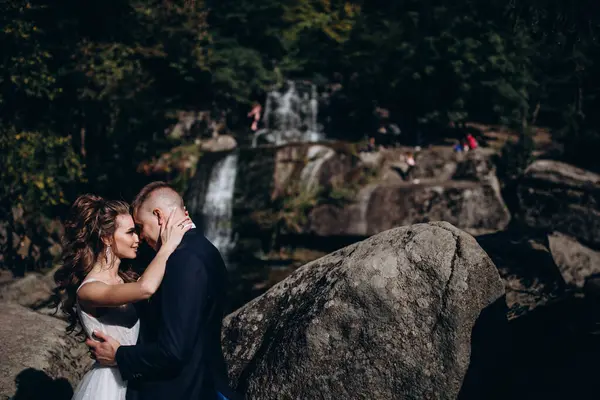Güzel, mutlu gelin ve damat düğün günü parkta sarılıyorlar.      