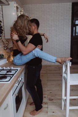 Güzel bir çift, arka planda Noel süsleriyle mutfakta şehvetle poz veriyor.