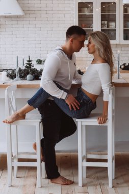 Uzun kollu beyaz elbiseli güzel bir çift mutfakta poz veriyor.