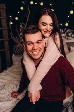 Stüdyoda rahat bir Noel süslemesiyle yatakta poz veren birbirine aşık genç bir çift. Yeni yılın aşk hikayesi.. 