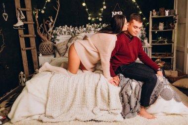 Stüdyoda rahat bir Noel süslemesiyle yatakta poz veren birbirine aşık genç bir çift. Yeni yılın aşk hikayesi.. 