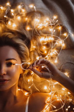 Güzel genç bir kadın Noel süsleriyle yatakta yatıyor.