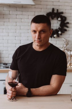 Genç bir adam modern bir mutfakta güven içinde poz verir..