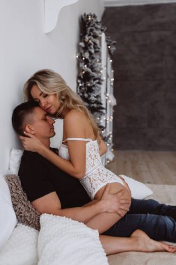 Birbirine aşık çiftler, yatakta şehvetle poz veriyorlar. Yılbaşı dekorasyonları var.