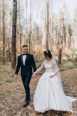 Mutlu gelin ve damat düğün günü ormanda yürüyor.
