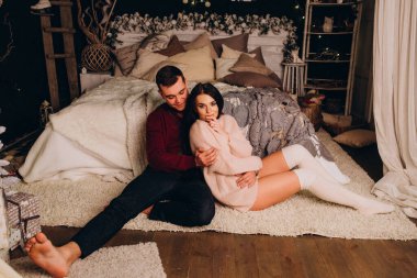 Stüdyoda rahat bir Noel süslemesiyle yatakta poz veren birbirine aşık genç bir çift. Yeni yılın aşk hikayesi.. 