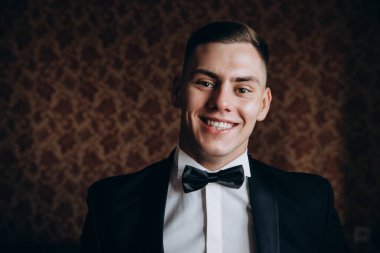 Şık takım elbiseli ve papyonlu yakışıklı genç adamın portresi.     