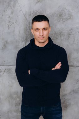 Genç adam stüdyoda poz veren siyah kapüşonlu günlük kıyafetler giyiyor.. 