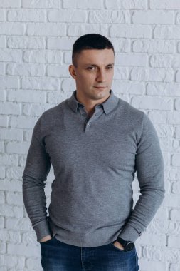 Stüdyoda poz veren sıradan kıyafetler giymiş genç yakışıklı bir adam. 